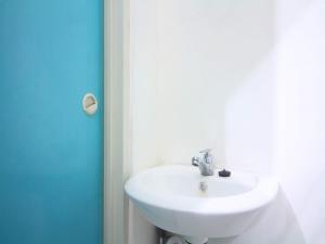La salle de bains est pourvue d'un lavabo blanc et d'une porte bleue. dans l'établissement LUMUNGGA KOSTEL By Hans Management, à Lampung 4 autres photos