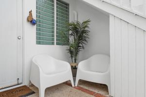 Deux chaises blanches assises à côté d'une table avec une plante dans l'établissement Ocean Park Beach Apart 1, à San Juan 33 autres photos