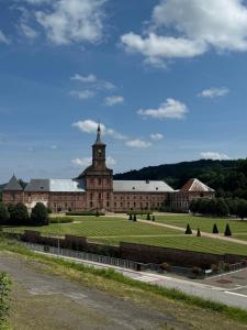 a large building with a clock tower on top of a field at Gite Mirabelle in Moyenmoutier