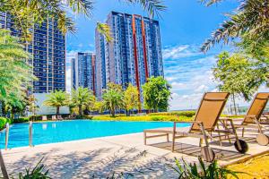 a group of chairs and a swimming pool with tall buildings at Peaceful Luxury at Tresor Klang by HCK in Petaling Jaya