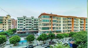 a large building with cars parked in a parking lot at GreenTree Inn Guangzhou Baiyun International Airport Huaxi Road Express Hotel in Guangzhou