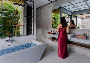 a woman in a red dress standing in front of a bathroom at Vinna Villa Seminyak by The Wina Resorts in Kerobokan +44 photos