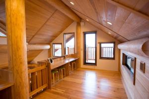 a large room with wooden floors and wooden beams at 大室山の麓ログハウスすくすく in Ito