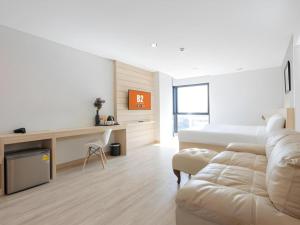 a white living room with a couch and a bed at B2 Don Mueang Premier Hotel in Bangkok