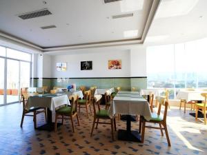 a dining room with tables and chairs and windows at GreenTree Inn Fuzhou Gulou District West Xierhuan Road Zuohai Park in Fuzhou