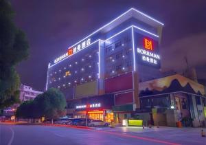 a building with a sign on top of it at night at Borrman Hotel Nanning Railway Station in Nanning
