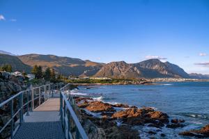 a bridge over the ocean with mountains in the background at 116 The Esplanade in Hermanus