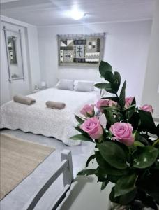 a bedroom with a bed and a vase with pink roses at Klein Plaasjapie apartment- Hebron Guest Farm in Malmesbury