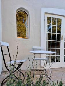 two chairs and a table in front of a building at Klein Plaasjapie apartment- Hebron Guest Farm in Malmesbury