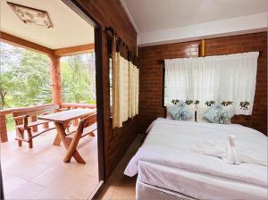 Schlafzimmer mit einem Bett und einem Tisch auf dem Balkon in der Unterkunft ศศิคันทรี รีสอร์ท in Suan Phung