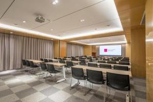a conference room with tables and chairs and a screen at Echarm Hotel Jinan Railway Station Daming Lake in Jinan