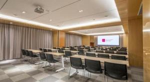 a conference room with tables and chairs and a screen at Echarm Hotel Jinan Railway Station Daming Lake in Jinan