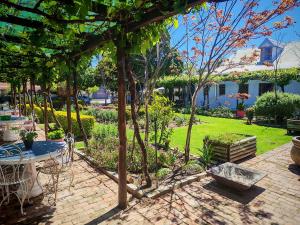 a patio with a table and chairs in a garden at Villa ChoCoLatt Guest House and Porta Taverna Restaurant in Porterville