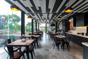 a restaurant with tables and chairs in a room at Zoom Dharmahusada Hotel in Surabaya