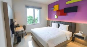 a bedroom with a large bed with a purple wall at Zoom Dharmahusada Hotel in Surabaya +104 photos