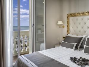 a bedroom with a bed with a view of the ocean at Novecento Suite Hotel in Riccione