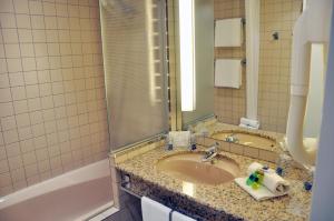 a bathroom with a sink, mirror and bath tub at Novotel Andorra in Andorra la Vella