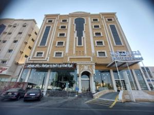a large building with cars parked in front of it at ساتورن هاوس للشقق الفندقية in Tabuk