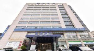 Un edificio alto con un cartel delante. en Starway Hotel Hongqiao Junction Center Branch, en Shanghái