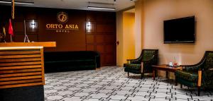 ビシュケクにあるOrto Asia Hotel Bishkekのバーと椅子とテレビのあるホテルのロビー