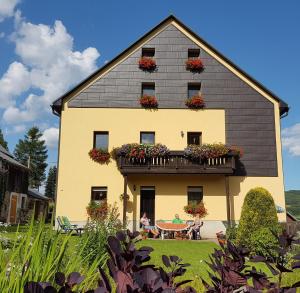 a house with people sitting at a table in front of it at 2-Personen-Apartment in Oberwiesenthal