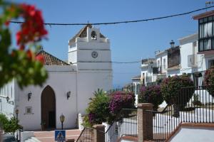 a white building with a clock tower on a street at Apartamentos Balcón de Maro in Maro