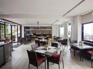 Un comedor con mesas y sillas y ventanas. en Kenari Tower Hotel, en Makassar