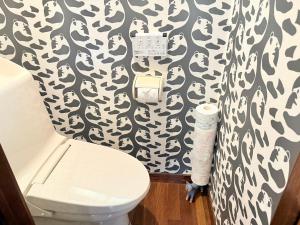 a bathroom with a toilet and a black and white wallpaper at コテージそら豆ん家 in Nasu