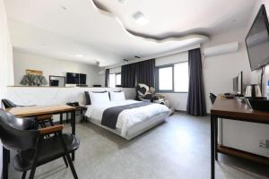 a bedroom with a bed and a desk and a tv at Hotel Look in Daejeon