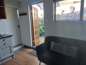 a living room with a black couch and a door at Fevertree cottage in Bloemfontein