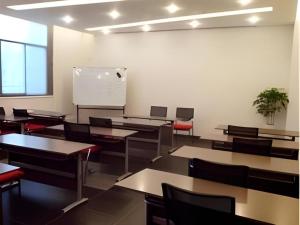 an empty classroom with tables and chairs and a whiteboard at Fairyland Hotel Kunming Tuodong Branch in Kunming