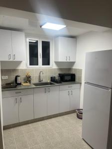 a kitchen with white cabinets and a white refrigerator at Beautiful studio on Tel Aviv beach in Tel Aviv