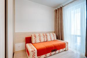 an orange chair in a room with a window at Apartament Przy Latarni in Kołobrzeg