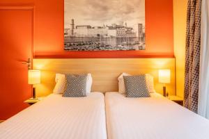 two beds in a hotel room with orange walls at Comfort Aparthotel Marseille Prado in Marseille