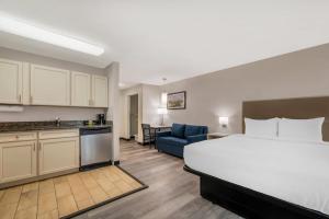 a hotel room with a bed and a kitchen at MainStay Suites Sterling near Dulles Town Center in Sterling
