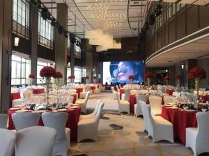 a banquet hall with tables and chairs and a screen at Huading International Hotel in Hangzhou