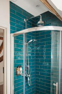 a blue tiled bathroom with a shower with blue tiles at Ty Mawr, The Old School Holiday Homes in Llanwrtyd Wells