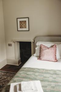 a bed with a pink pillow on top of it at Ty Mawr, The Old School Holiday Homes in Llanwrtyd Wells