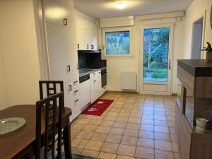 una cocina con armarios blancos, una mesa y una puerta en Appartement le Refuge du Cerisier, en La Chaux-de-Fonds