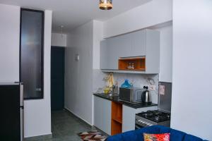 a kitchen with white cabinets and a stove top oven at Tsavo Stanley kiambu Road in Gatunga