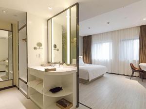 une salle de bain avec un lavabo, un lit et un miroir dans l'établissement Ibis Styles Chengdu Chunxi Taikoo Li Hotel, à Chengdu 173 autres photos
