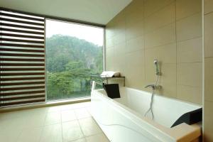 bagno con vasca e telefono appeso al muro di Symphony Suites Hotel a Ipoh