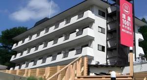 a white building with a red sign in front of it at Kinugawa Niouson Plaza Hotel in Nikko
