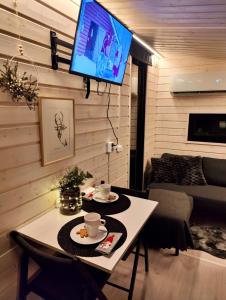 a living room with a table and a tv on a wall at Little Elves Cabin in Rovaniemi