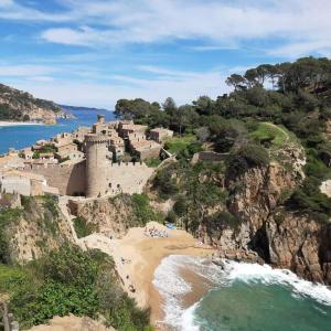 a castle on a cliff next to a beach at St Jordi Hagdigadar Tossa in Tossa de Mar