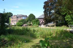 una grande casa in un campo con erba e alberi di Ferienwohnung Lavendel a Brüggen