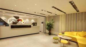 a living room with a yellow couch and a table at Borrman Hotel Zhuhai Gongbei Port Fuhuali Light Rail in Zhuhai