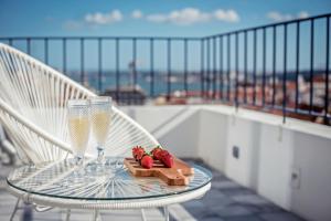 里斯本的住宿－希亞多阿爾梅利亞珍藏公寓，阳台上的玻璃桌,配有2杯玻璃杯和草莓