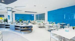 a restaurant with white tables and chairs and blue walls at Jinjiang Inn Luoyang Wangcheng Park Metro Station in Luoyang