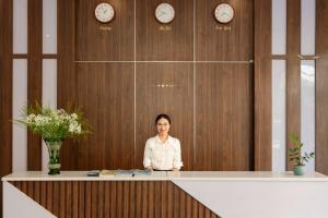 a woman sitting at a counter in a room with clocks at Hygg Hotel Phu Quoc in Phu Quoc